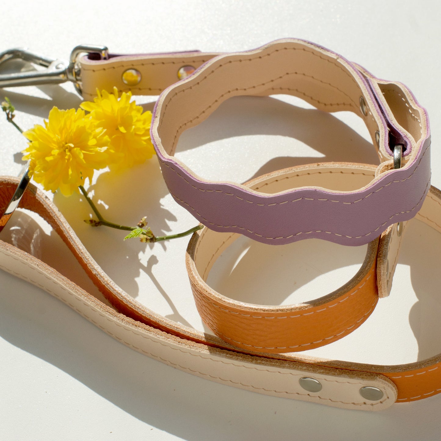 a bicolored wavy leash folded, showing both colors - lila and pumpkin on one side, and the natural vegetable tanned leather on the other side.